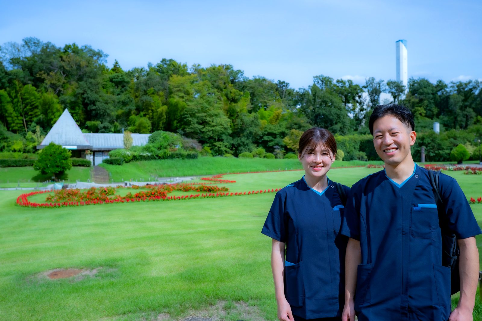 緑あふれる公園に立つあさぎ訪問看護リハビリステーションのスタッフ